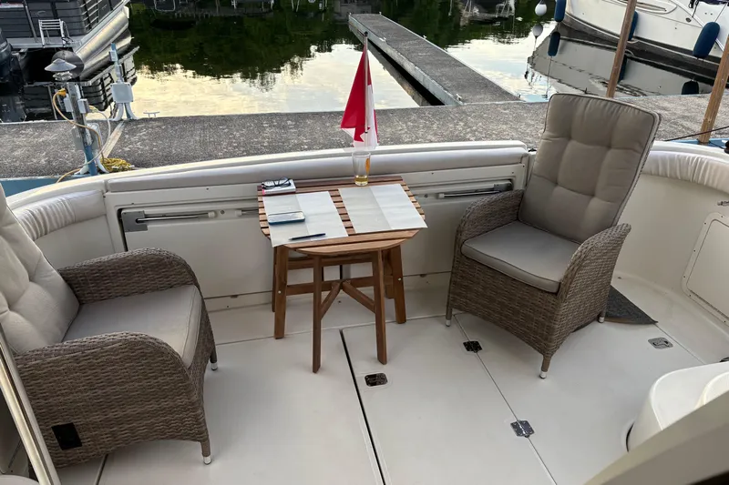  Yacht Photos Pics 2003 Regal Commodore 3880 yacht deck with chairs, table, and flag at marina.