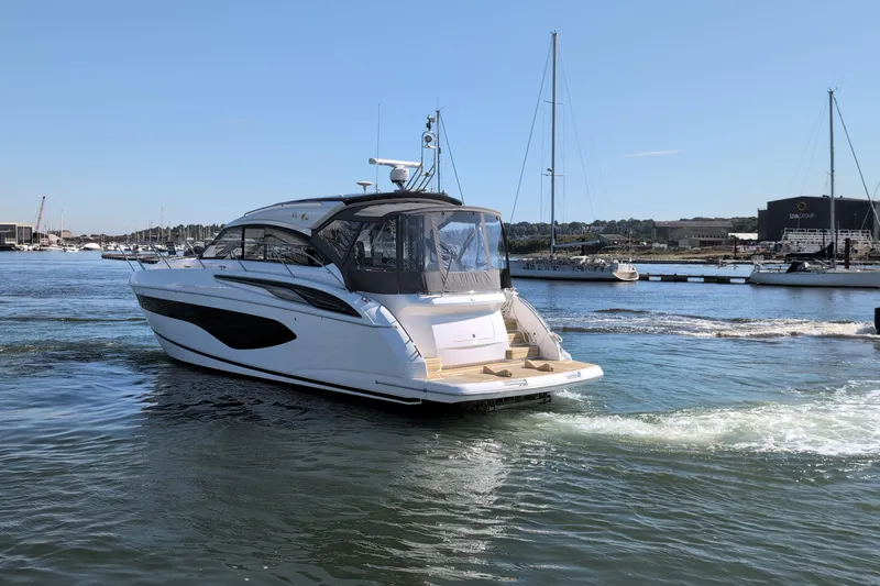  Yacht Photos Pics Luxury 2021 Princess V50 yacht cruising in a marina under clear blue skies.