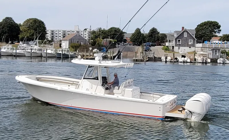 Carly Rose Yacht Photos Pics 2023 Regulator 34 boat cruising in a marina with coastal buildings in the background.
