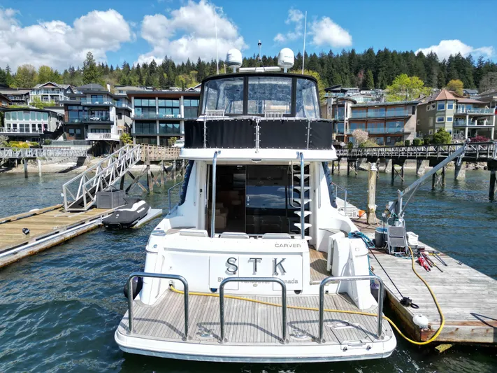  Yacht Photos Pics 2001 Carver 570 Voyager Pilothouse docked at a scenic waterfront with houses.