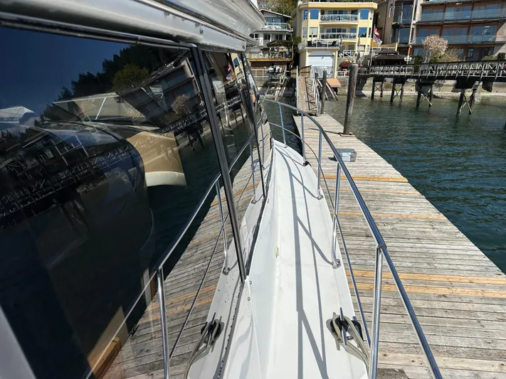  Yacht Photos Pics 2001 Carver 570 Voyager Pilothouse docked at a wooden pier, reflecting waterfront buildings.