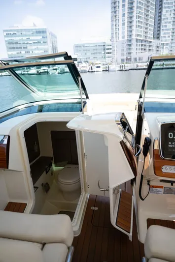 Dunton Yacht Photos Pics 2021 Chris-Craft Launch GT boat interior with open cabin door, docked near modern buildings.
