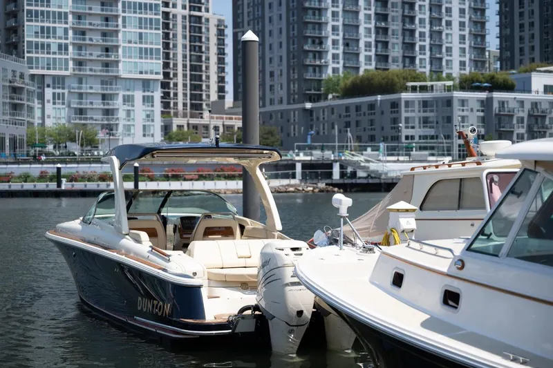 Dunton Yacht Photos Pics 2021 Chris-Craft Launch GT boat docked in urban marina with modern buildings.