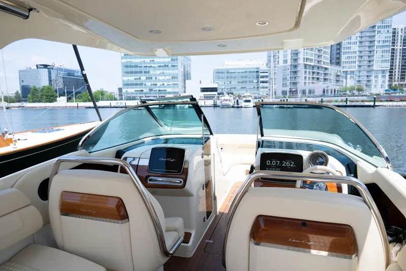 Dunton Yacht Photos Pics 2021 Chris-Craft Launch GT interior with modern dashboard, luxurious seating, and waterfront cityscape view.