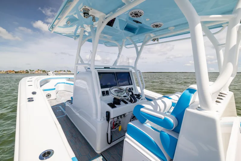  Yacht Photos Pics 2023 Yellowfin 36 Offshore boat interior with blue and white seating, steering console, and ocean view.