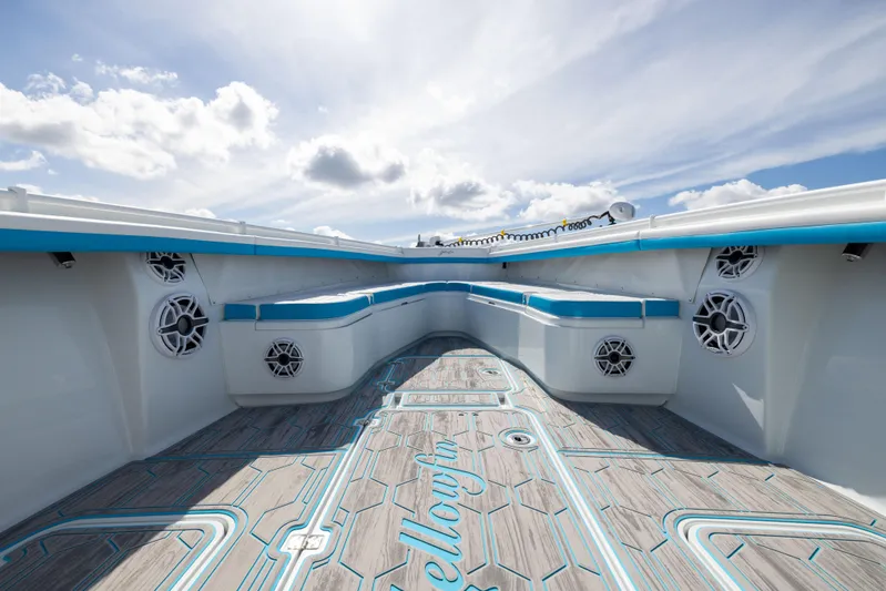  Yacht Photos Pics 2023 Yellowfin 36 Offshore boat interior with blue accents and speakers under a cloudy sky.