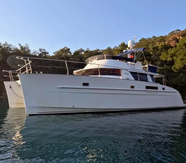 Kungaloosh Yacht Photos Pics 2010 Fountaine Pajot Cumberland 46 yacht on calm water, surrounded by trees.