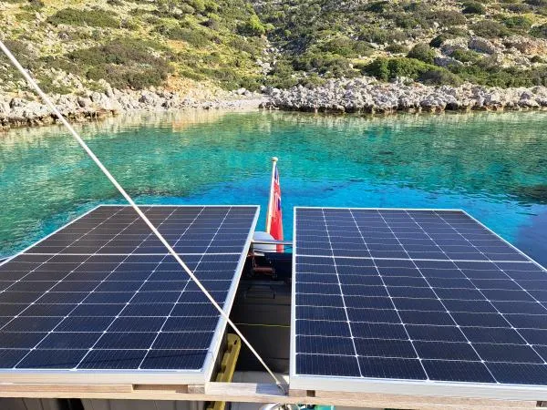 Kungaloosh Yacht Photos Pics Solar panels on a 2010 Fountaine Pajot Cumberland 46, near a scenic rocky shoreline.