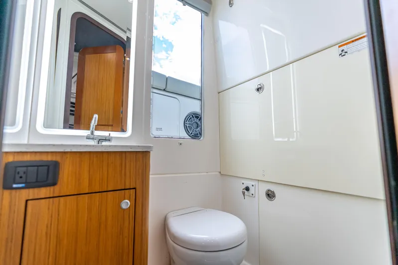 Two Roads Yacht Photos Pics Modern bathroom interior of 2021 Solace 41CS boat with wooden cabinetry and compact toilet.