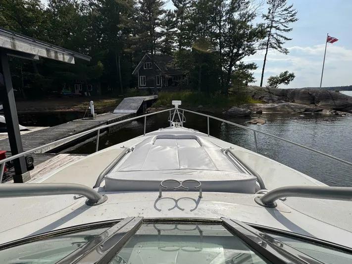  Yacht Photos Pics 2008 Donzi 38 ZSF boat docked by a lakeside cabin with trees and a flag.