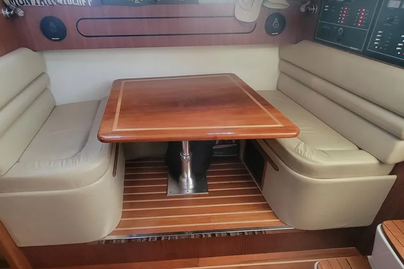 Valkyrie Yacht Photos Pics 2004 Pursuit 3400 Offshore cabin with wooden table and cushioned seating.