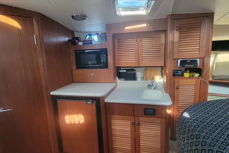 Valkyrie Yacht Photos Pics 2004 Pursuit 3400 Offshore yacht interior with kitchenette, featuring wood cabinetry and modern appliances.