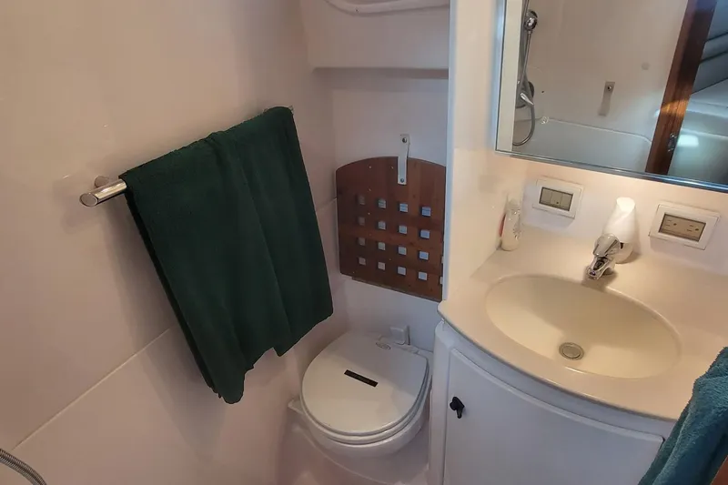 Valkyrie Yacht Photos Pics Compact bathroom in 2004 Pursuit 3400 Offshore boat with sink, toilet, and towel.