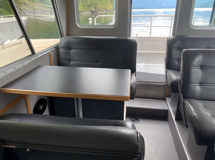  Yacht Photos Pics Interior of 2005 Coastal Craft 32 boat with black leather seating and table, overlooking water.