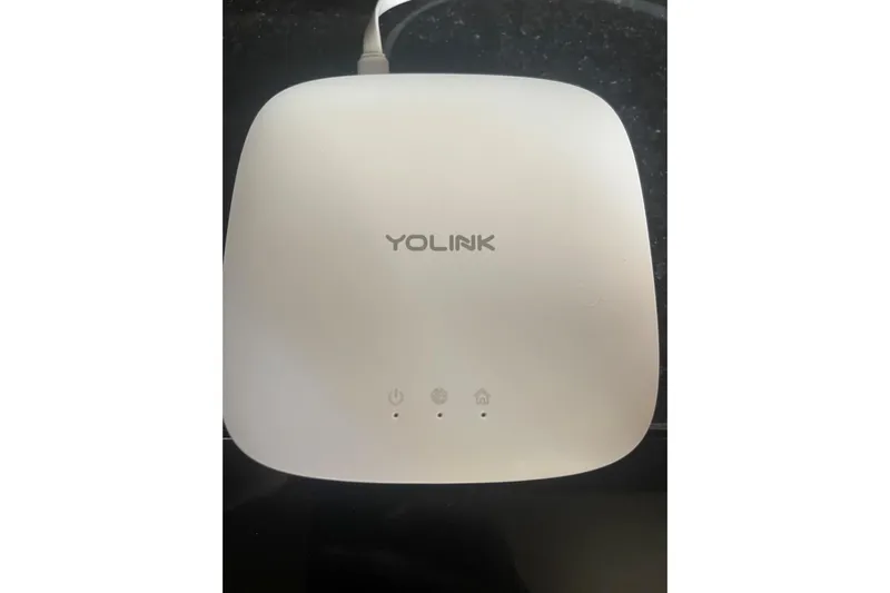  Yacht Photos Pics White YoLink smart home device with LED indicators on a black surface.