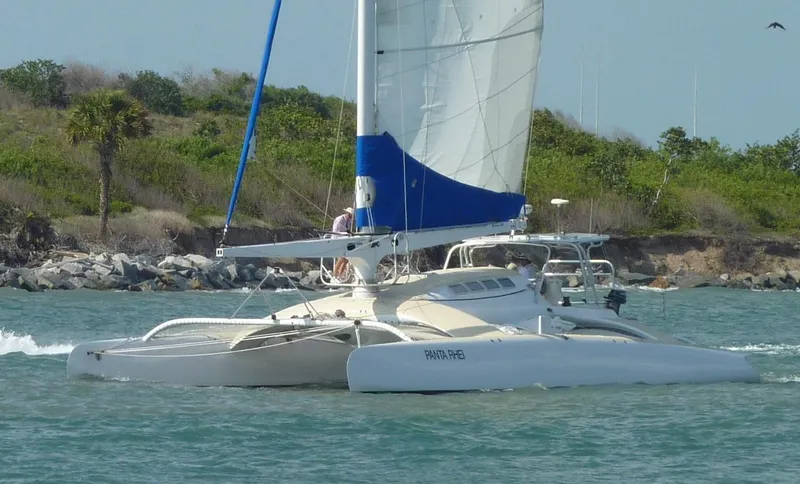 Panta Rhei Yacht Photos Pics Custom Roake 50 catamaran sailing near a rocky shoreline, 2012 model.