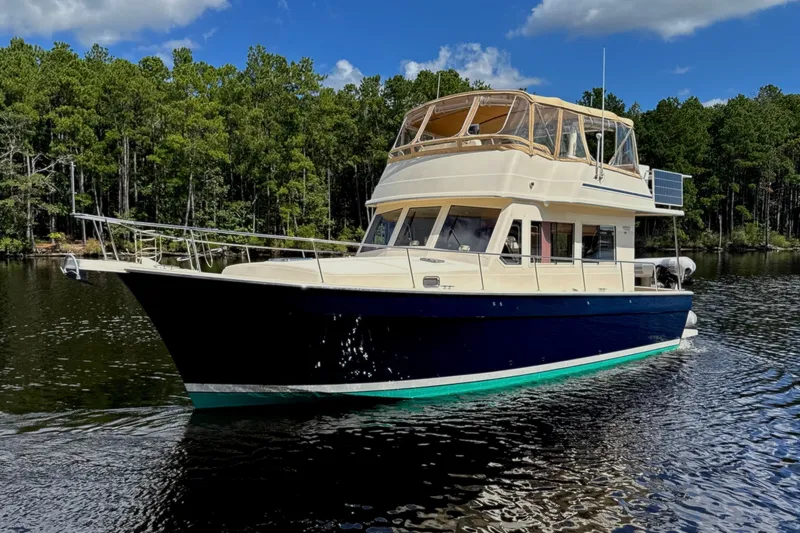 Blue Note Yacht Photos Pics 2007 Mainship 430 Trawler cruising on a serene lake with forest backdrop.