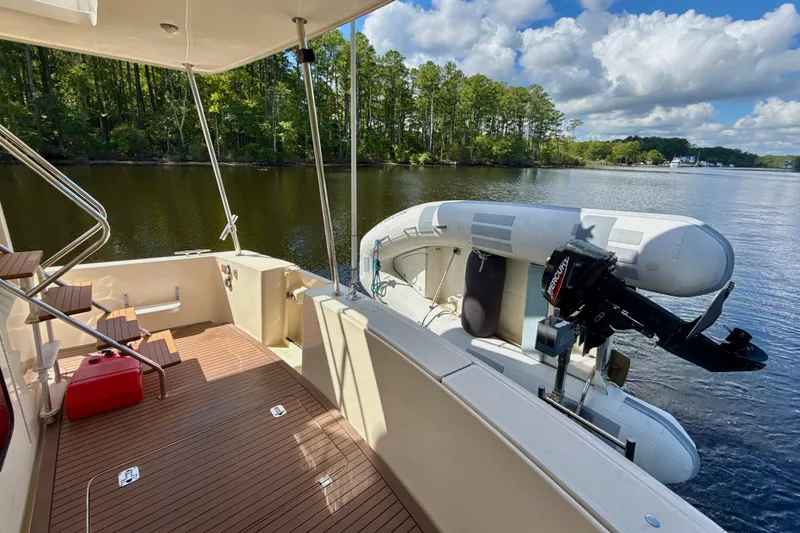 Blue Note Yacht Photos Pics 2007 Mainship 430 Trawler with dinghy on calm lake, surrounded by lush trees.