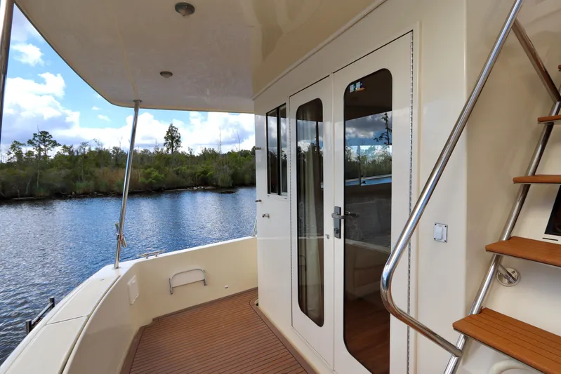Blue Note Yacht Photos Pics 2007 Mainship 430 Trawler deck with glass doors and wooden steps, overlooking serene waterway.