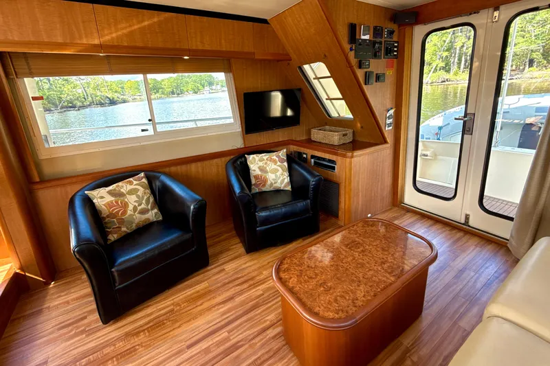 Blue Note Yacht Photos Pics Interior of 2007 Mainship 430 Trawler with leather chairs, wood accents, and scenic window view.