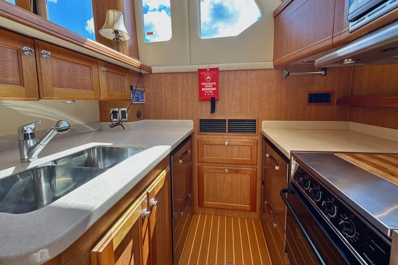 Blue Note Yacht Photos Pics 2007 Mainship 430 Trawler kitchen with wooden cabinets, stainless steel sink, and modern appliances.
