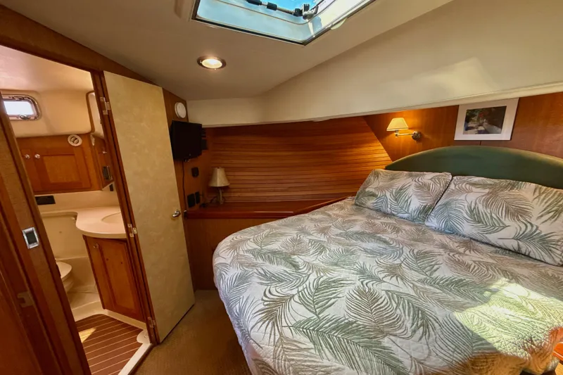 Blue Note Yacht Photos Pics 2007 Mainship 430 Trawler bedroom with skylight, cozy bed, and adjacent bathroom.