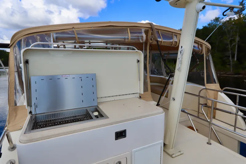 Blue Note Yacht Photos Pics 2007 Mainship 430 Trawler with outdoor grill on deck, surrounded by scenic waterway.