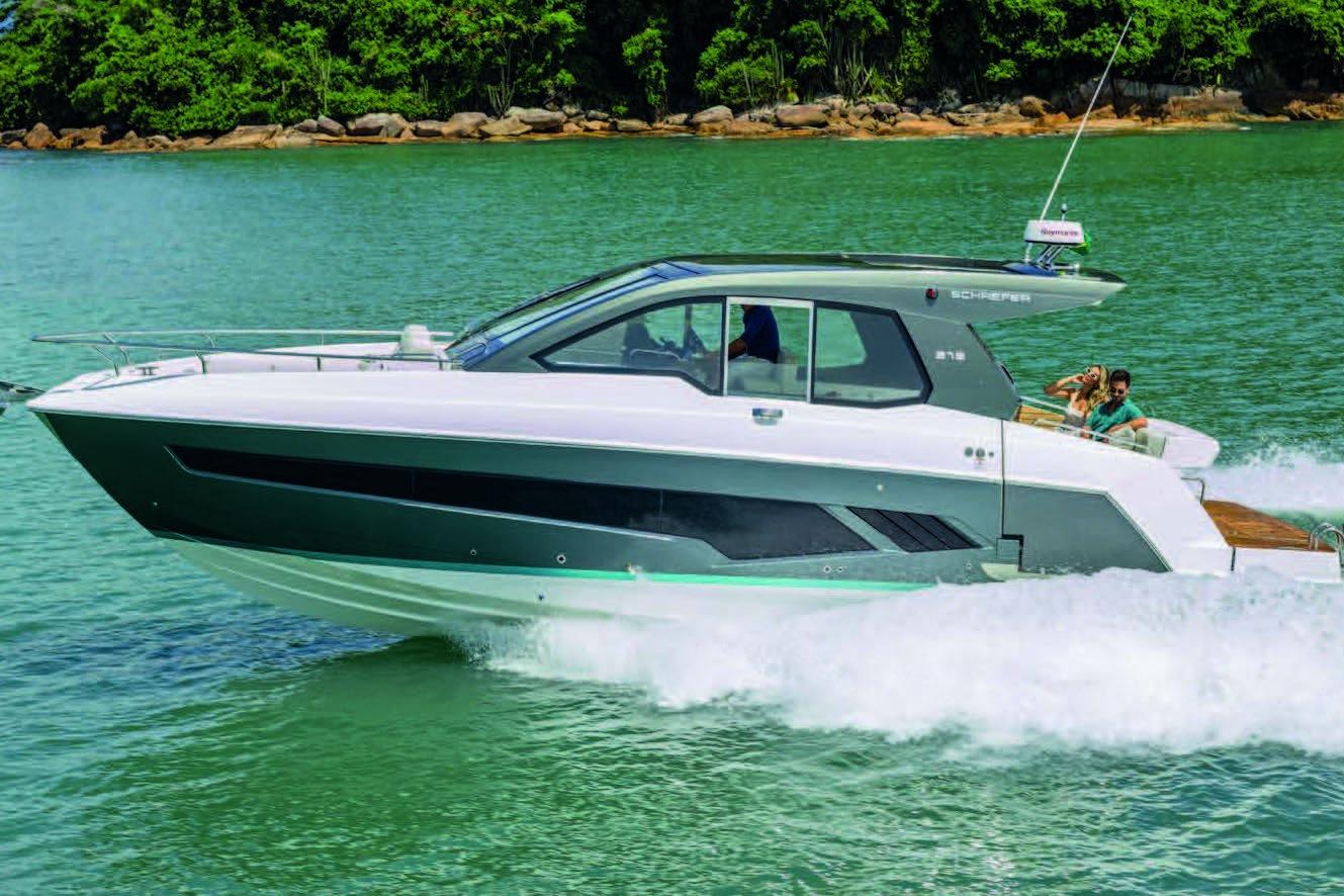 2025 Schaefer 375 HT yacht cruising on turquoise water near lush shoreline.