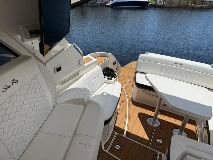  Yacht Photos Pics 2021 Sea Ray Sundancer 350 Coupe interior with white seating and wooden deck by the water.