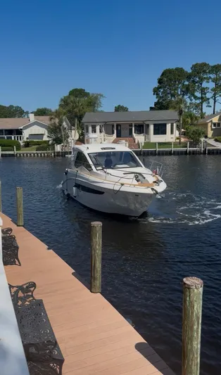  Yacht Photos Pics 2021 Sea Ray Sundancer 350 Coupe cruising on a sunny day near waterfront homes.