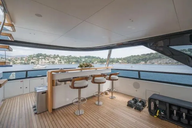  Yacht Photos Pics Luxurious 2023 Benetti Motopanfilo 37M yacht deck with bar stools and scenic waterfront view.