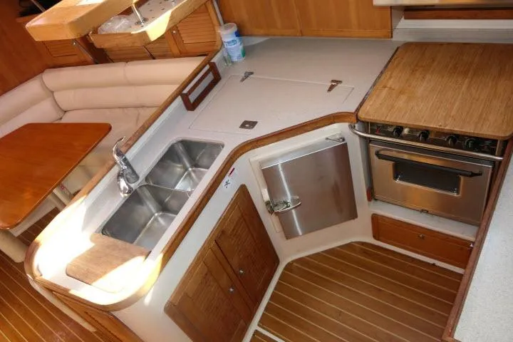 Right Action Yacht Photos Pics 2008 Catalina 400 MK II yacht kitchen with stove, sink, and wooden cabinetry.