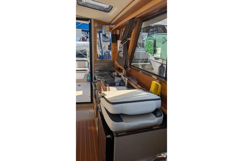 Kameleon Yacht Photos Pics Interior of 2017 Cutwater C28 boat showing kitchen area with seating and window.