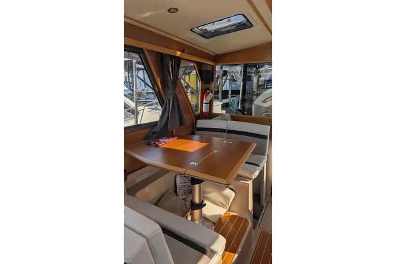 Kameleon Yacht Photos Pics 2017 Cutwater C28 boat interior with dining area, wooden table, and cushioned seating.