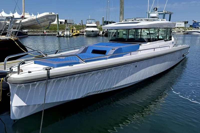  Yacht Photos Pics 2024 Axopar 37 XC CROSS CABIN boat docked in a marina, featuring sleek design and blue accents.