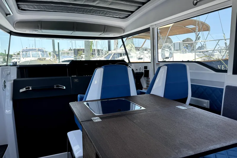  Yacht Photos Pics 2024 Axopar 37 XC CROSS CABIN interior with blue seating and wooden table.