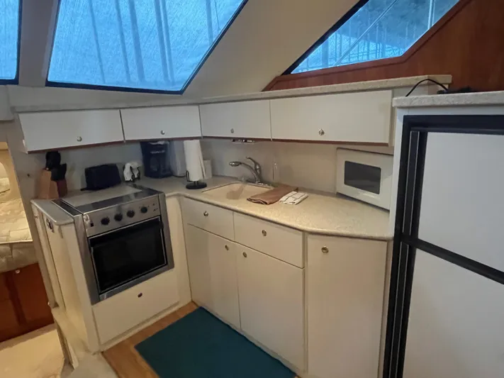  Yacht Photos Pics 1999 Silverton 392 Aft Cabin kitchen with stove, sink, and microwave under skylight.
