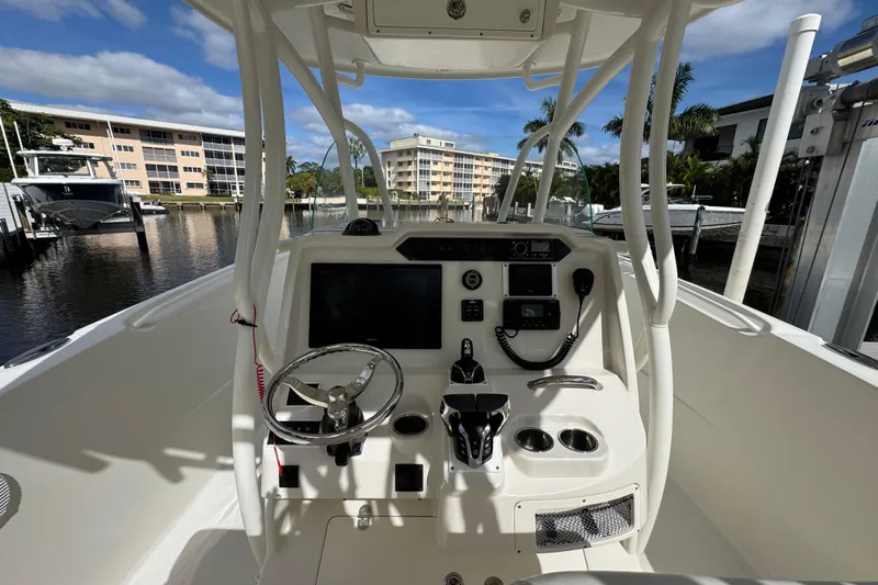  Yacht Photos Pics 2016 Sailfish 320 CC boat cockpit with steering wheel and control panel, docked near waterfront buildings.