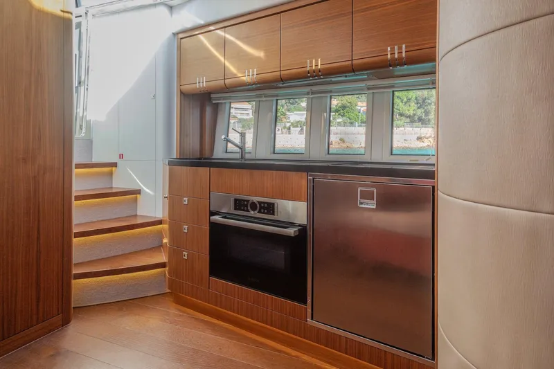 Tyma Yacht Photos Pics Modern kitchen interior on 2019 Windy 46 Chinook yacht, featuring wood cabinetry and stainless steel appliances.