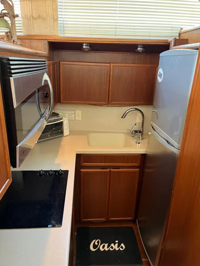Oasis Yacht Photos Pics Compact kitchen in a 1990 Hatteras Motor Yacht with modern appliances and wooden cabinetry.