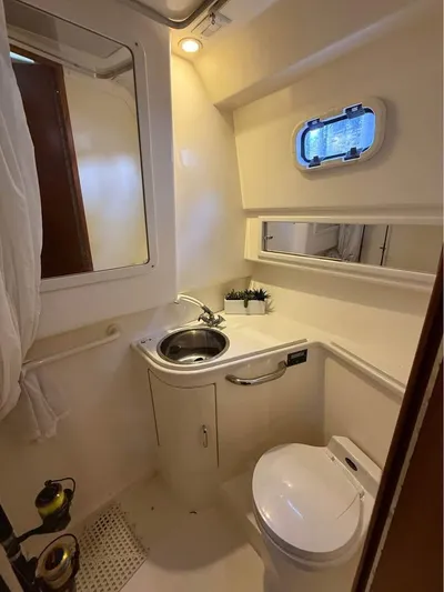  Yacht Photos Pics 2001 Cabo 35 Express boat bathroom with sink, toilet, and porthole window.