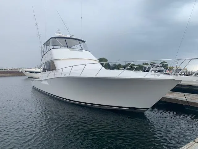  Yacht Photos Pics 2002 Viking 55 Convertible yacht docked in calm waters under cloudy skies.