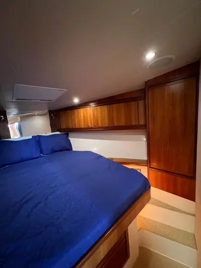 No Name Yacht Photos Pics 2009 Bertram 45 Convertible cabin with blue bedding and wooden cabinetry.