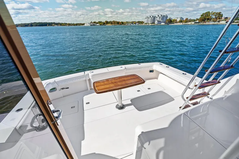 Bella Vita Yacht Photos Pics 2010 Bertram Convertible yacht deck with table, overlooking serene waters and distant shoreline.