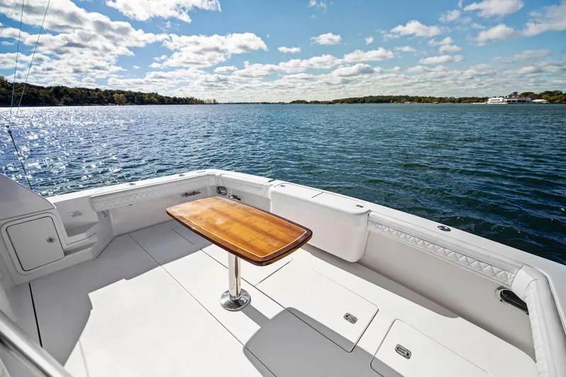 Bella Vita Yacht Photos Pics 2010 Bertram Convertible boat deck with wooden table, overlooking serene lake and sky.