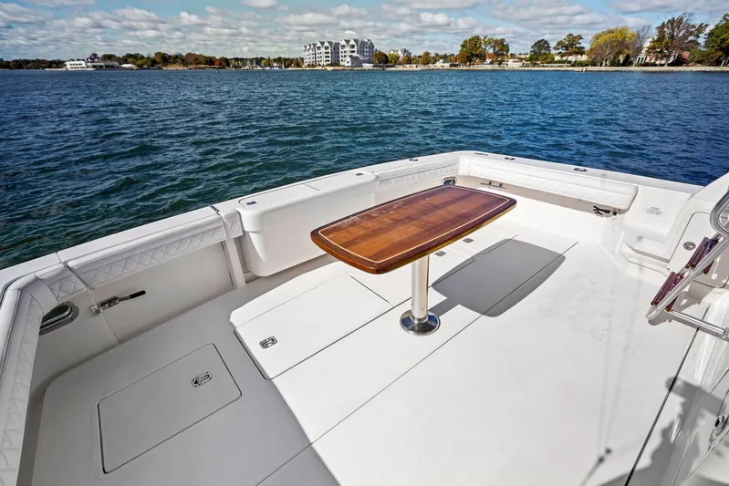 Bella Vita Yacht Photos Pics Spacious deck of 2010 Bertram Convertible boat with wooden table, overlooking serene waters.