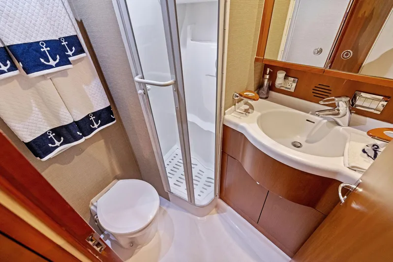 Bella Vita Yacht Photos Pics Bathroom interior of 2010 Bertram Convertible yacht with shower, sink, and nautical-themed towels.