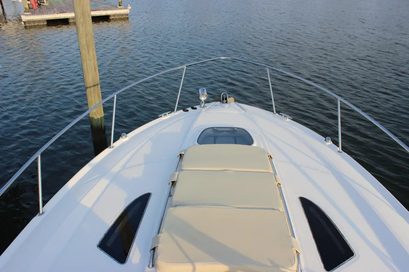  Yacht Photos Pics 2012 Sea Ray 330 Sundancer yacht bow view with sun pad, docked on calm water.
