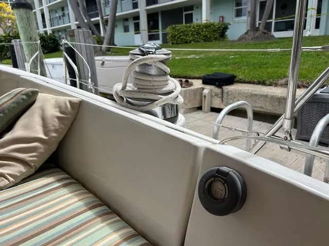 Walkabout Yacht Photos Pics Beneteau Oceanis 461 sailboat deck with winch and striped cushions, docked near greenery.