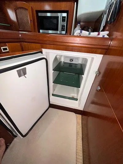 Walkabout Yacht Photos Pics Interior of 1997 Beneteau Oceanis 461 yacht showing open refrigerator and wooden cabinetry.